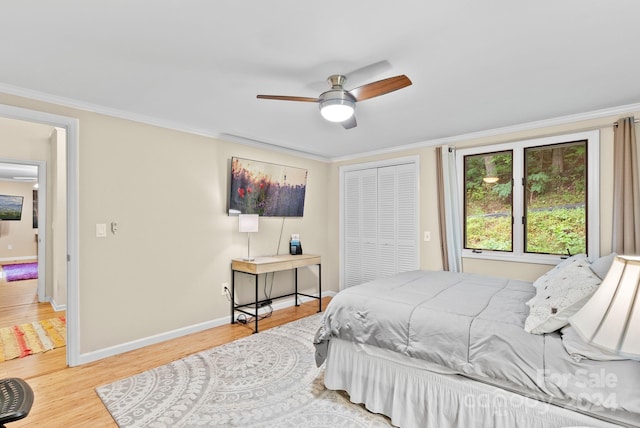 bedroom featuring a closet, baseboards, crown molding, and wood finished floors