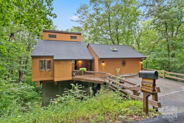 exterior space featuring a shingled roof and a deck