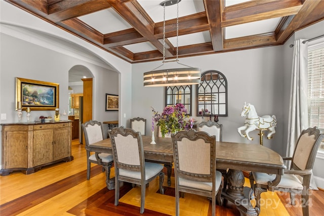 dining space featuring crown molding, an inviting chandelier, beamed ceiling, coffered ceiling, and hardwood / wood-style flooring