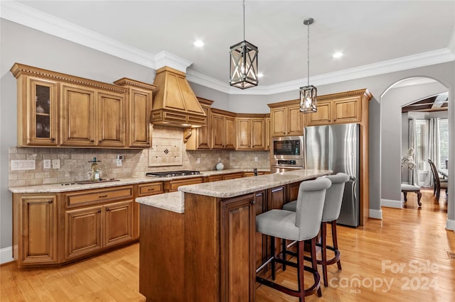 kitchen featuring custom exhaust hood, stainless steel appliances, crown molding, light hardwood / wood-style flooring, and backsplash