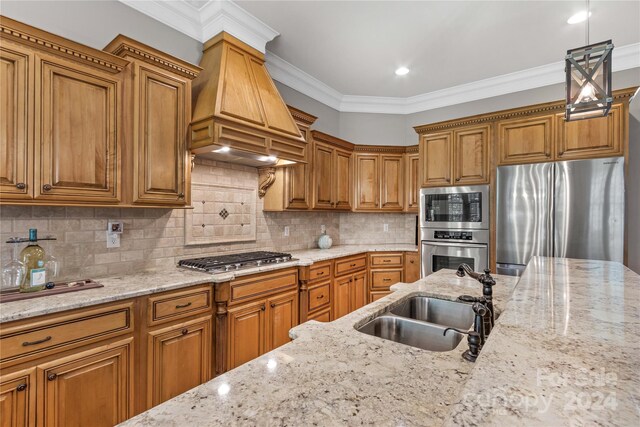 kitchen with appliances with stainless steel finishes, sink, pendant lighting, premium range hood, and decorative backsplash