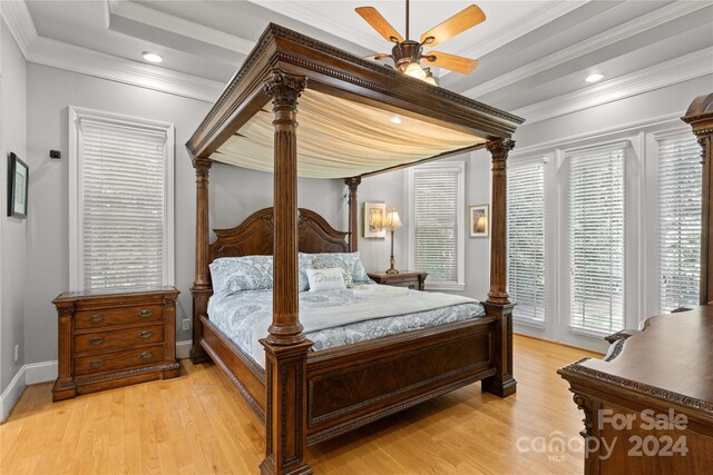 bedroom featuring light hardwood / wood-style floors, a raised ceiling, ornamental molding, and ceiling fan