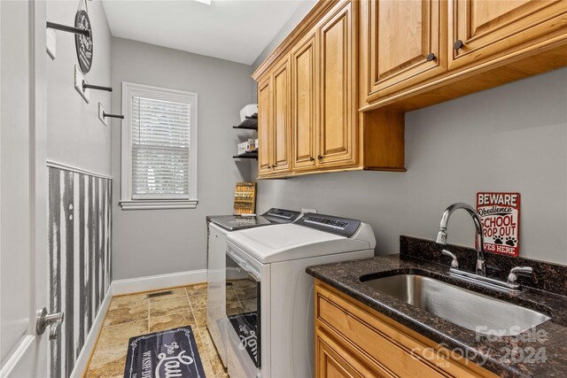 laundry room featuring cabinets, light tile patterned floors, washing machine and dryer, and sink