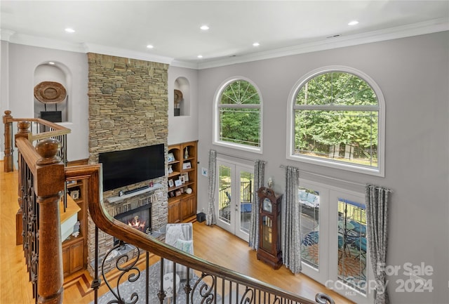 living room with ornamental molding, a fireplace, french doors, and light hardwood / wood-style floors