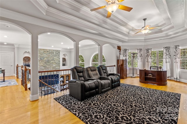 living room with ceiling fan, crown molding, a tray ceiling, and light hardwood / wood-style floors