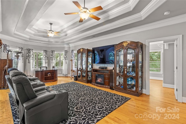 living room featuring ceiling fan, crown molding, a tray ceiling, and light hardwood / wood-style floors