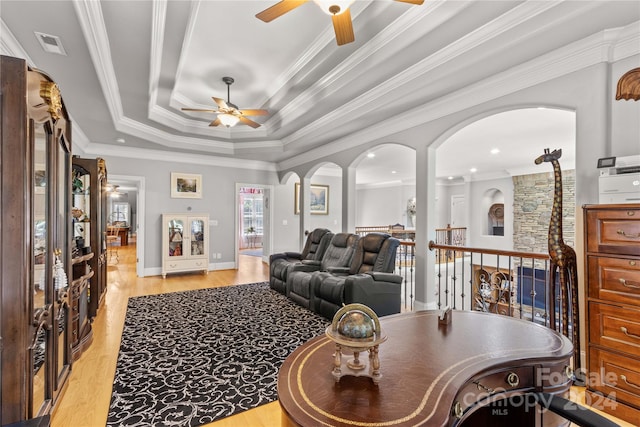 living room featuring light hardwood / wood-style floors, ceiling fan, a raised ceiling, and crown molding