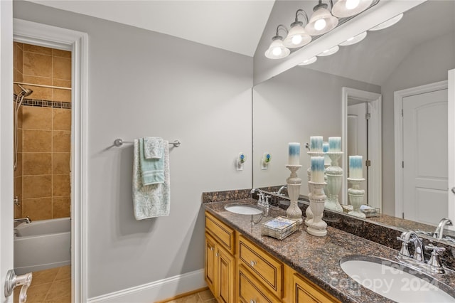 bathroom featuring double vanity, tile patterned floors, vaulted ceiling, and tiled shower / bath