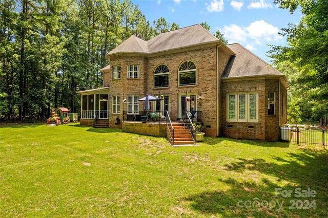 back of property with a sunroom and a lawn