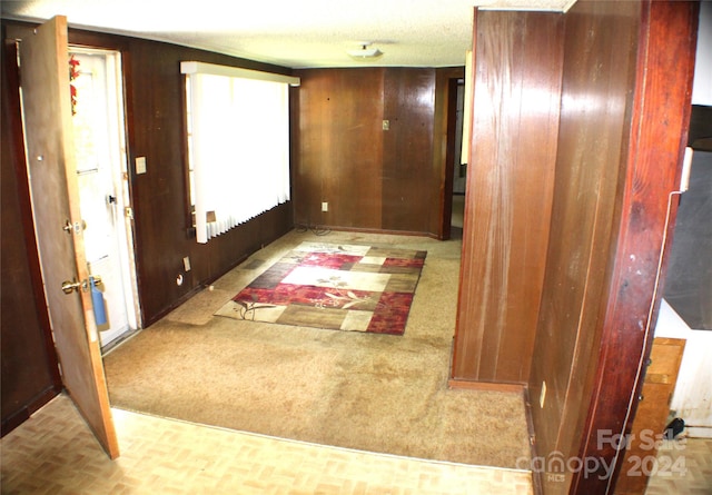 corridor with light colored carpet and wood walls