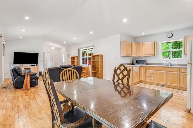 dining space featuring sink, vaulted ceiling, and light hardwood / wood-style flooring