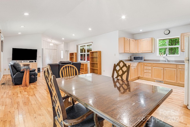 dining area featuring lofted ceiling, sink, and light wood-type flooring