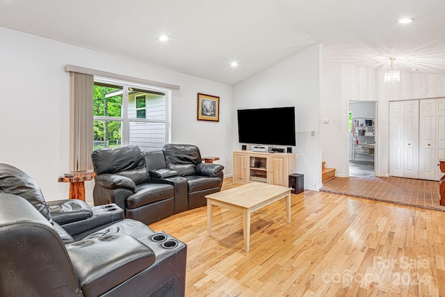 living room featuring vaulted ceiling, light hardwood / wood-style flooring, and a notable chandelier