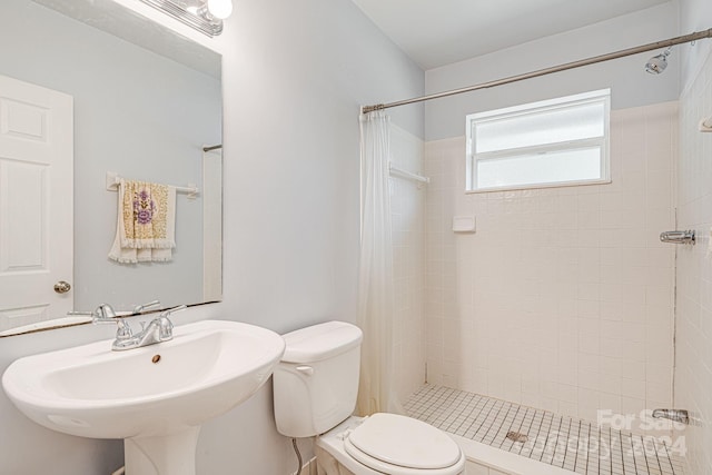 bathroom with walk in shower, sink, and toilet