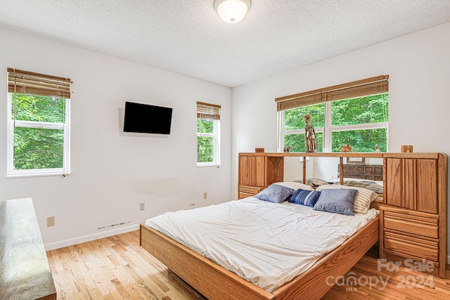 bedroom with a textured ceiling and light wood-type flooring