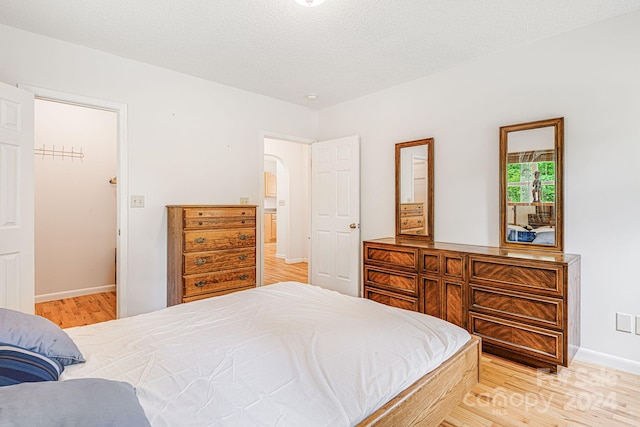 bedroom with a closet, a textured ceiling, and light wood-type flooring