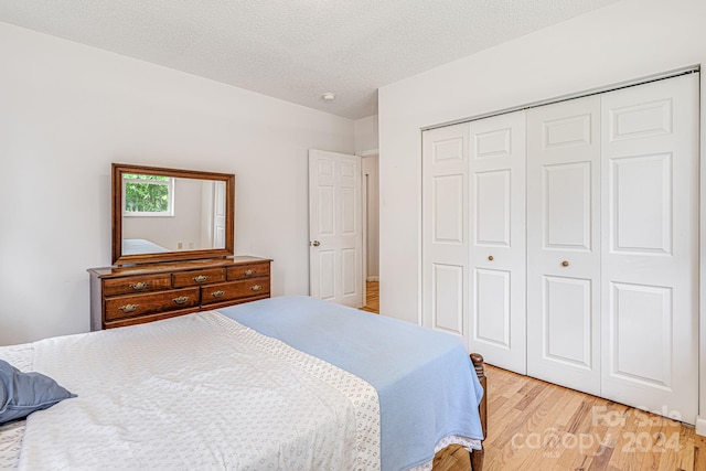 bedroom with light hardwood / wood-style flooring, a textured ceiling, and a closet