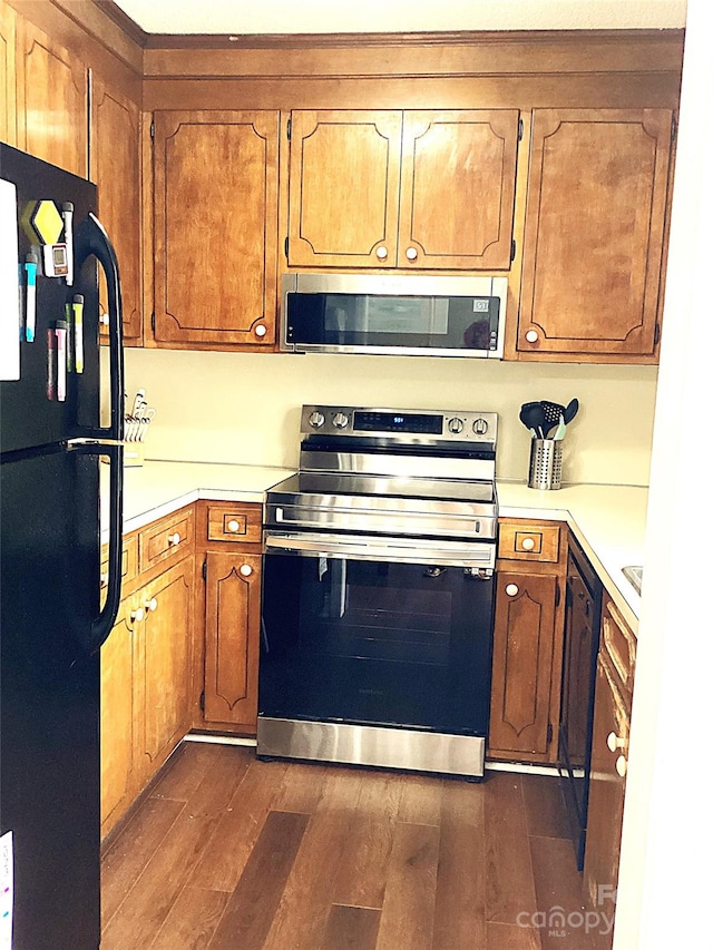 kitchen with black appliances and dark hardwood / wood-style flooring