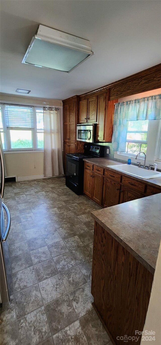 kitchen featuring tasteful backsplash, black electric range, and sink