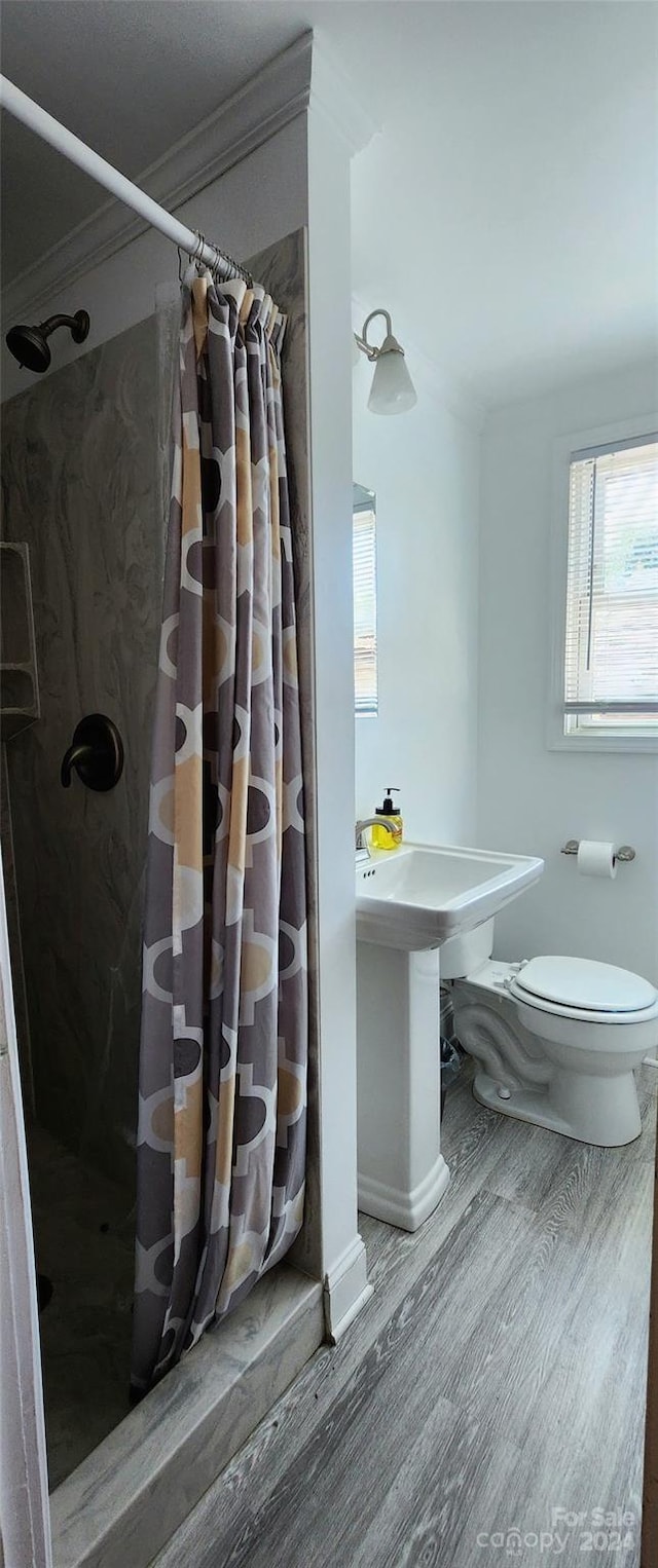 bathroom featuring a shower with shower curtain, toilet, ornamental molding, and hardwood / wood-style floors