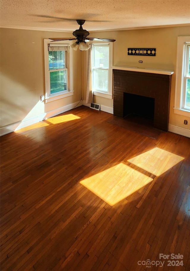 unfurnished living room with a textured ceiling, ceiling fan, dark hardwood / wood-style floors, and a brick fireplace