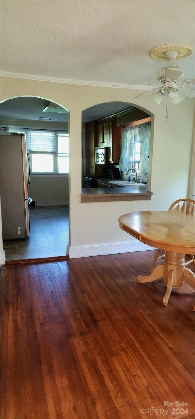 unfurnished dining area with ceiling fan, ornamental molding, dark hardwood / wood-style flooring, and a textured ceiling