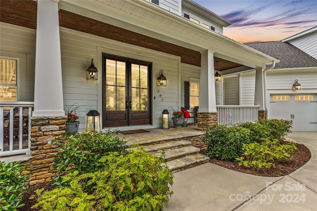 exterior entry at dusk featuring a garage and covered porch