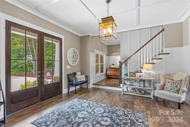 foyer entrance featuring coffered ceiling, a notable chandelier, french doors, and hardwood / wood-style floors