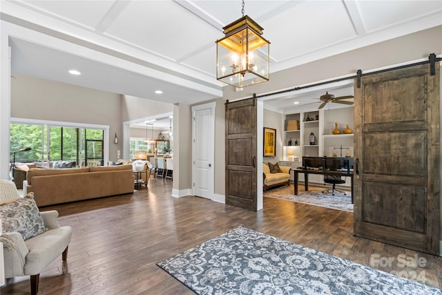 interior space with dark hardwood / wood-style floors, ceiling fan with notable chandelier, coffered ceiling, and a barn door