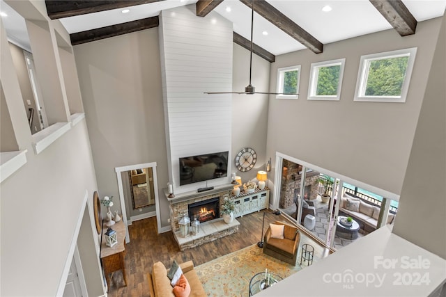 living room with beam ceiling, a fireplace, hardwood / wood-style floors, and high vaulted ceiling