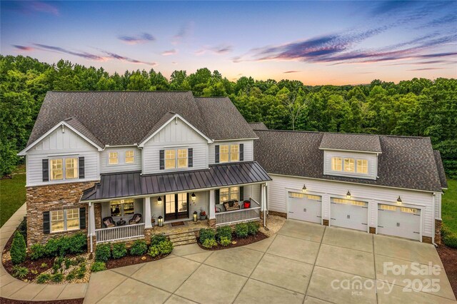 127 Tradition Ln, Mooresville, NC 28115 - view of front of house featuring a shingled roof, stone siding, board and batten siding, covered porch, and driveway