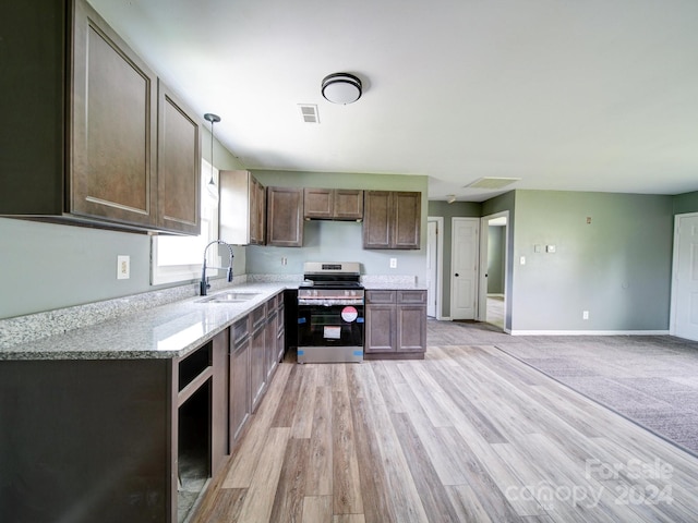 kitchen with pendant lighting, sink, electric range, light stone counters, and light hardwood / wood-style flooring