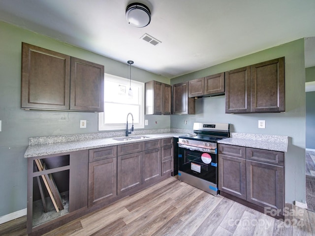 kitchen with stainless steel electric range oven, sink, hanging light fixtures, dark brown cabinetry, and light hardwood / wood-style floors