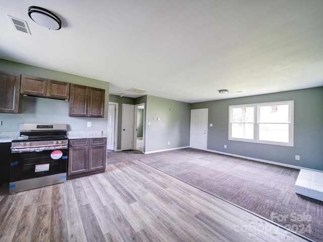 kitchen with dark brown cabinets, light wood-type flooring, and stainless steel electric range