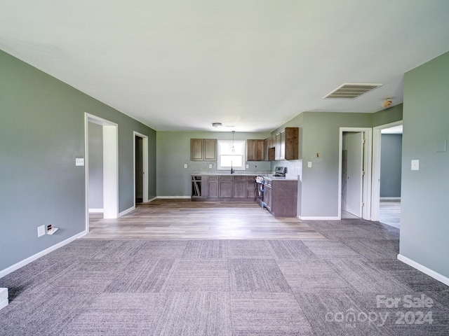 kitchen with stainless steel range, light colored carpet, and dishwasher