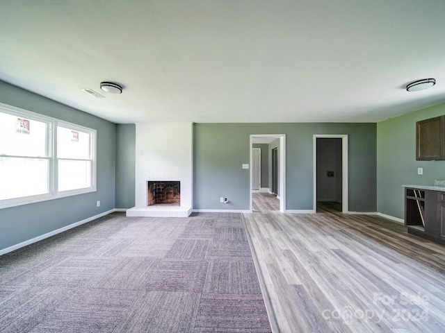 unfurnished living room featuring a brick fireplace and light hardwood / wood-style floors