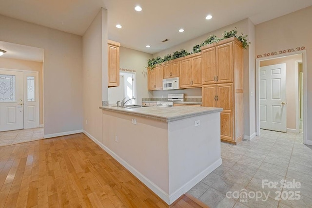 kitchen with tile countertops, recessed lighting, a sink, white appliances, and a peninsula