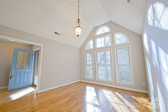 interior space featuring baseboards, visible vents, vaulted ceiling, and light wood finished floors