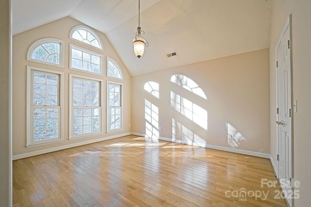 interior space featuring high vaulted ceiling, light wood-style flooring, and baseboards