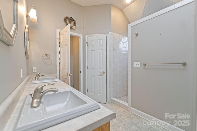 full bath with a tile shower, double vanity, and a sink