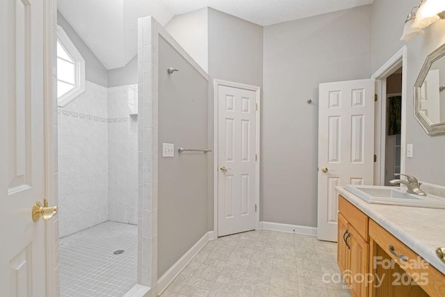 full bath featuring vaulted ceiling, baseboards, walk in shower, and vanity