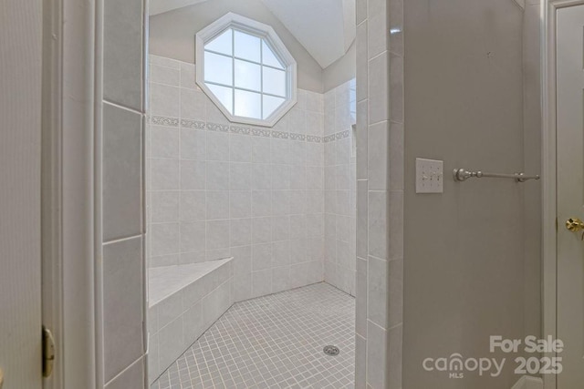 full bathroom with vaulted ceiling and a tile shower