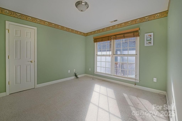 spare room with carpet, visible vents, and baseboards