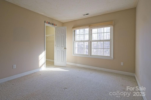 spare room with visible vents, a textured ceiling, and baseboards