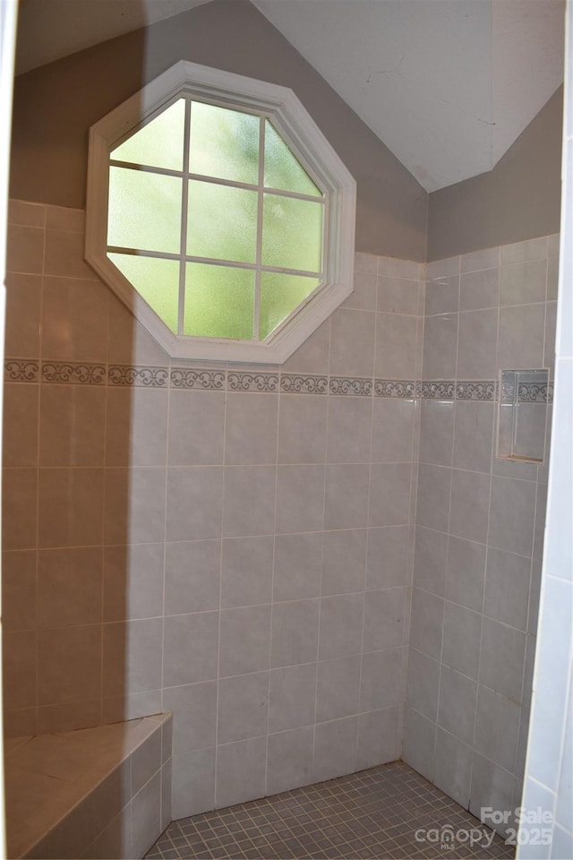 full bathroom with vaulted ceiling and tiled shower