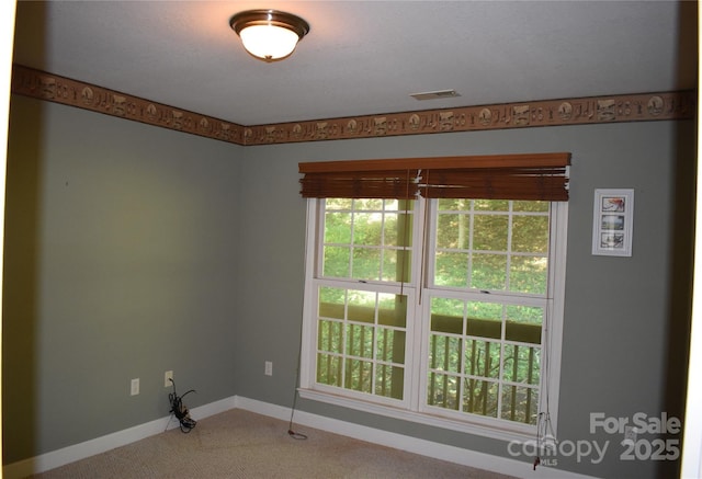 empty room featuring carpet, baseboards, and visible vents