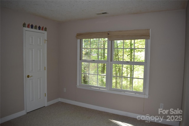 unfurnished room with a textured ceiling, visible vents, and baseboards