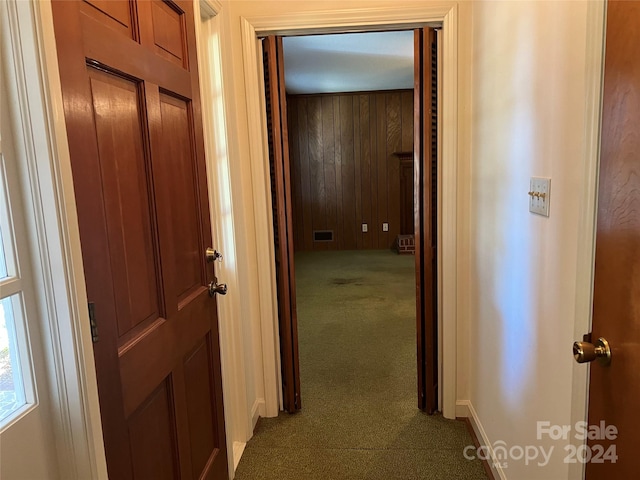 hall with wooden walls and carpet flooring