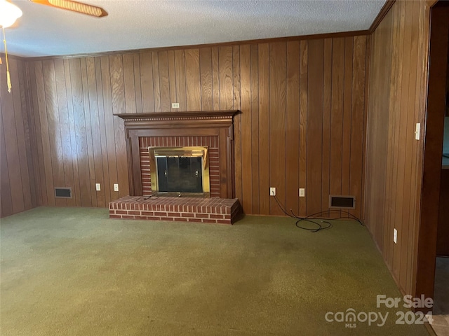 unfurnished living room with carpet, wood walls, ceiling fan, and a brick fireplace