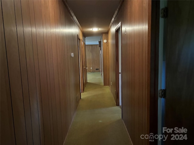 corridor with light carpet, wooden walls, and ornamental molding